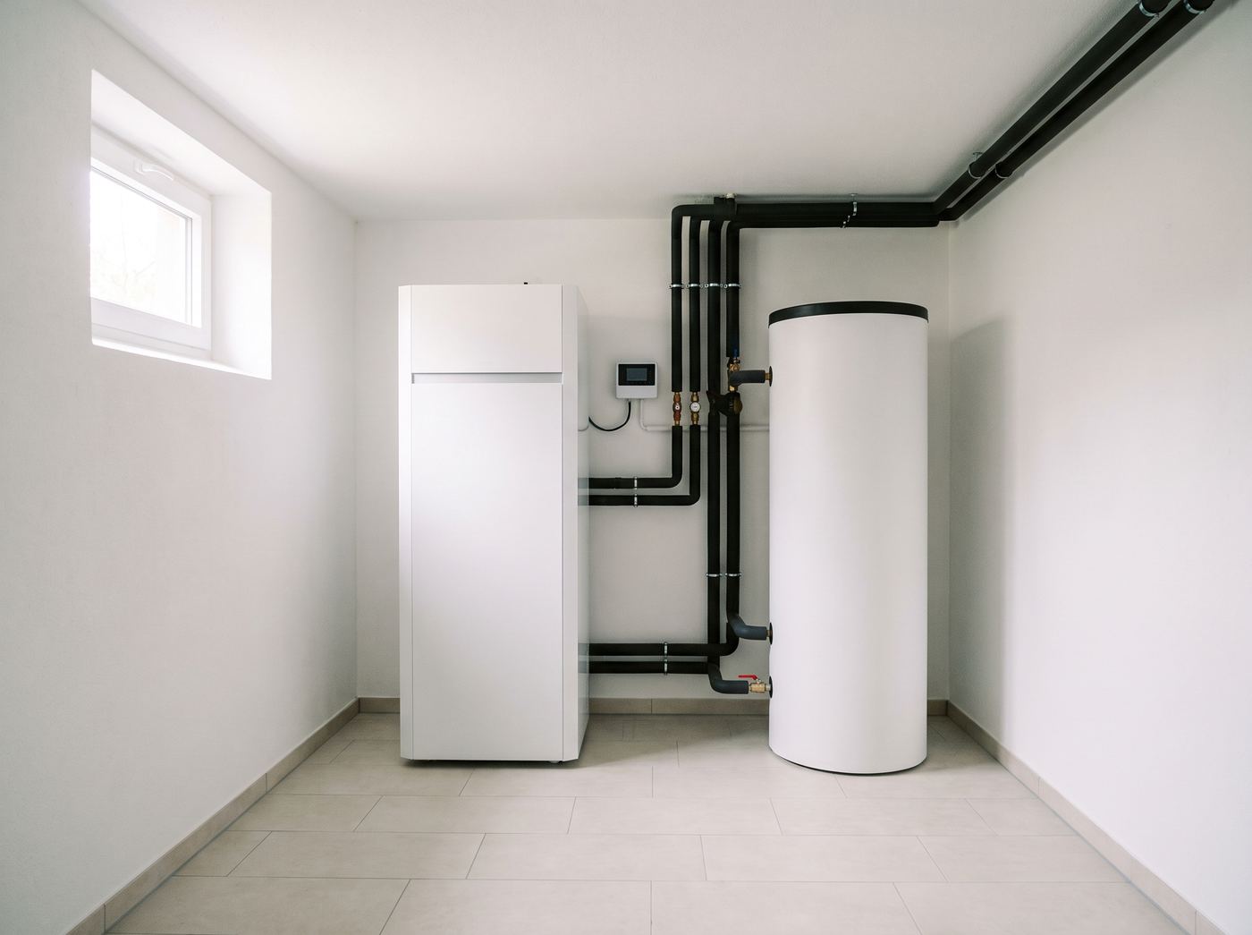 Nachher: heller Technikraum mit Inneneinheit der Wärmepumpe und Warmwasserspeicher